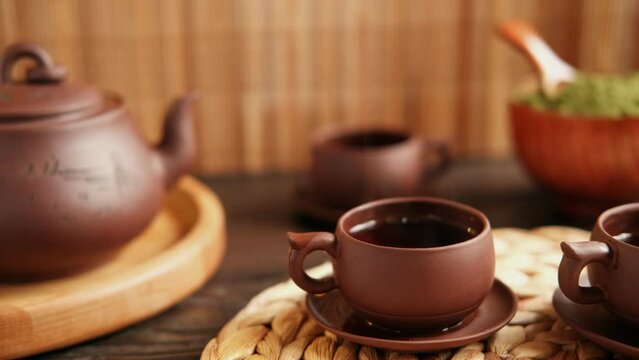 Tea Ceremony. Traditional Asian Tea Utensil, Serving Authentic Set. Person Pouring Tea from Brown Pottery Teapot to Teacup. Bamboo Tray. Lifestyle. Wellness Balance Health. Tea Brewing Equipment