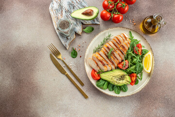 Fresh green salad with grilled chicken fillet, tomatoes, avocado, lemon on light background. Diet Concept. Top view copy space