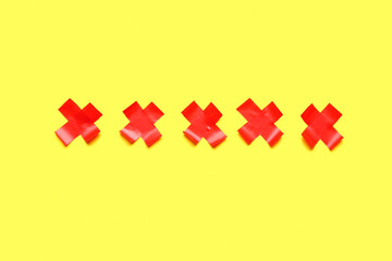 Obraz premium Red crosses made of adhesive tape on yellow background