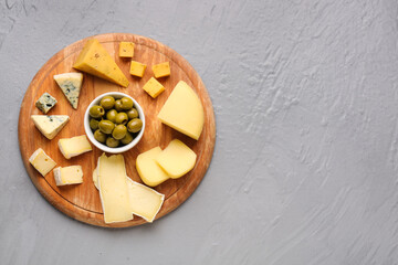 Fototapeta na wymiar Wooden board with pieces of tasty cheese on grey background