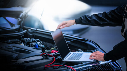 Computer diagnostics of the car in garage. Automotive mechanical technician using laptop computer...