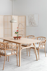 Dining table with beautiful ikebana in interior of room