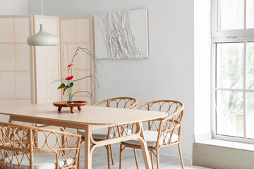 Dining table with beautiful ikebana in interior of room