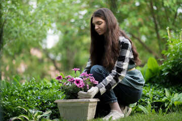 woman working outside in the garden and holding a pot with flowers planted in it