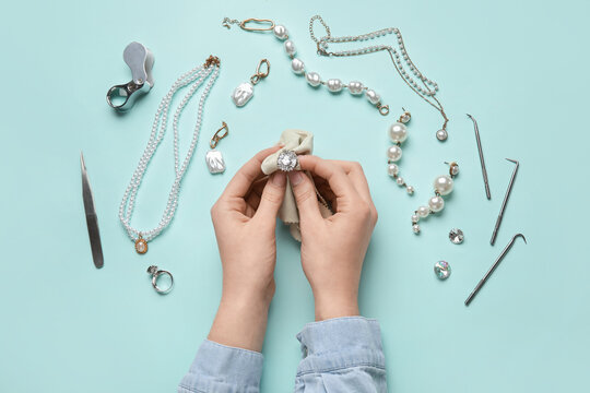 Female hands with beautiful jewelry and cleaning tools on color background