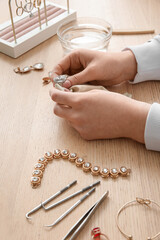 Woman polishing beautiful ring on wooden background, closeup
