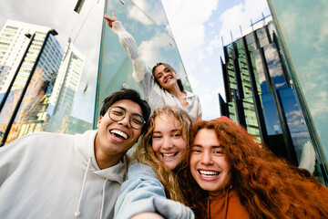 Group of happy young Gen Z friends taking self portrait for social media, standing in trendy and...