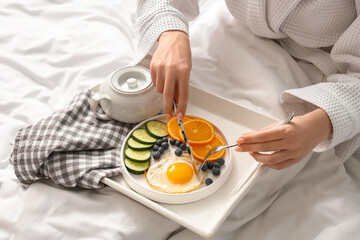 Obraz na płótnie Canvas Morning of young woman having breakfast in bedroom, closeup