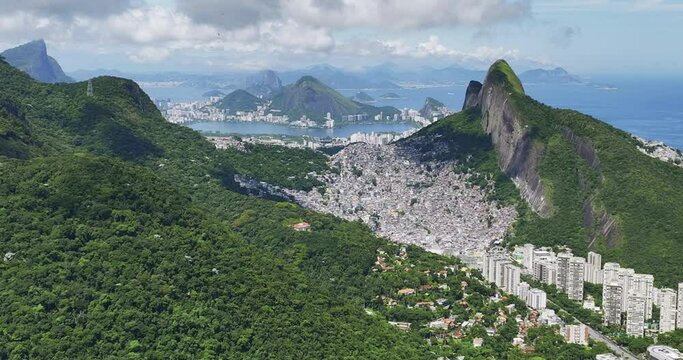 Aerial above green mountains towards Rio de Janeiro in background. Rocinha the largest favela in Brazil overlooking Rio on the slope of the mountain
