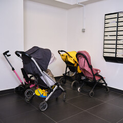 A pram in the entrance of an apartment building near the mailboxes. Baby strollers are in the...