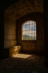 A dark prison room with bars preventing escape. Cold tower in castle in Spain. Cold stone walls.
