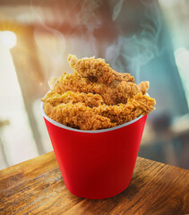 Fried Chicken hot crispy strips crunchy pieces of tenders in a Bucket - a large Red box on the table in the restaurant 
