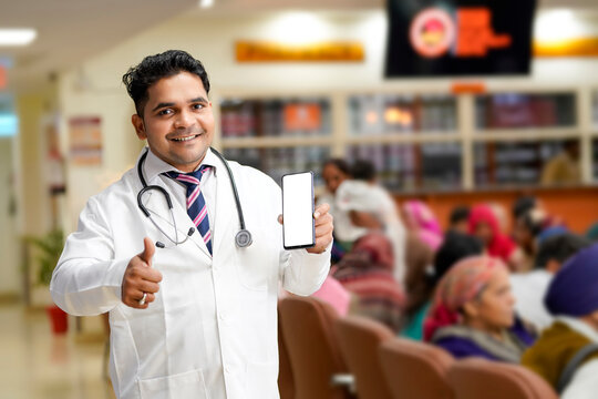 Indian male doctor showing smartphone screen at hospital.