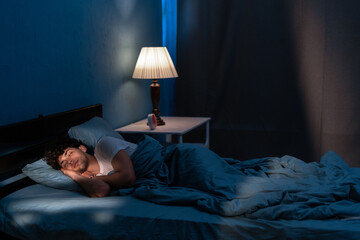 Young arabic man sleeping in bed at home at night. People, bedtime and rest concept