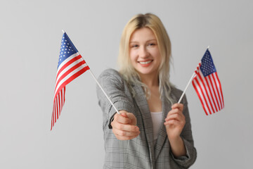 Young businesswoman with USA flags on grey background