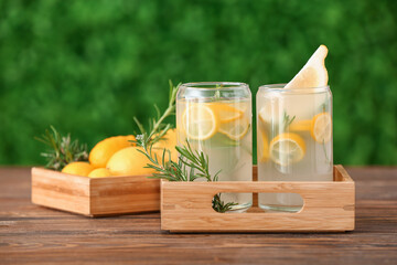 Wooden box of glasses with fresh lemonade on wooden table