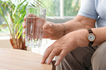 Senior woman with glass of water at home, closeup