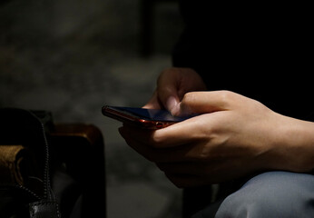 Business Woman’s hand typing on a phone in the shade