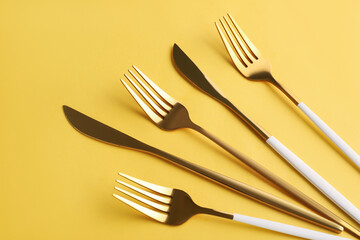 Stylish forks and knives on yellow background