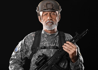 Mature soldier with assault rifle on dark background