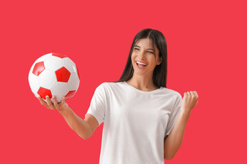 Happy young woman with soccer ball on red background
