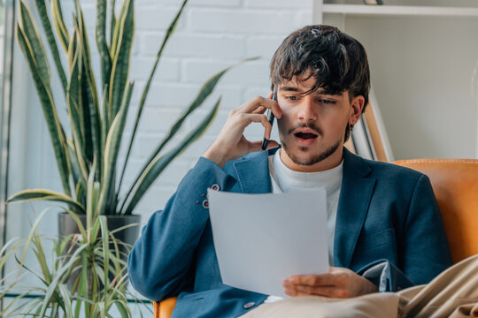 young man or student at home with document talking on mobile phone