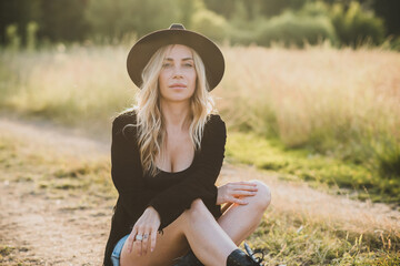 Freedom spirit. American girl at field. Young beautiful woman in Boho black fringe jacket and...