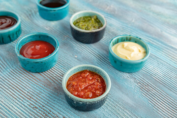 soy, pesto, mayonnaise, tkemali, ketchup, adjika sauces in clay bowls on wooden background