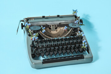 Vintage typewriter with flowers on blue background