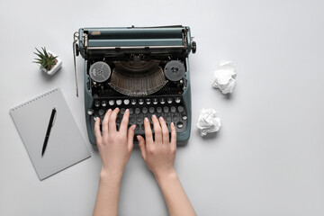 Woman typing on typewriter with notebook, houseplant and crumpled paper on white background