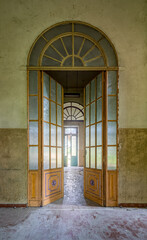 Vertikale Aufnahme einer schönen alten Glastür in einem verlassenem Gebäude. 