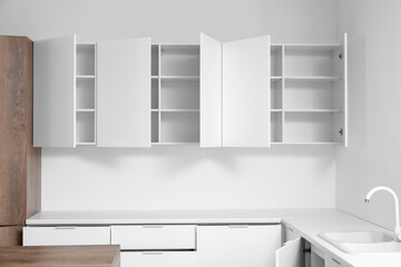 White cupboards hanging on light wall in kitchen