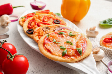 Plate with different tasty mini pizzas on white background