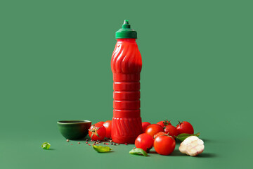 Bottle of ketchup and tomatoes with peppercorn on green background