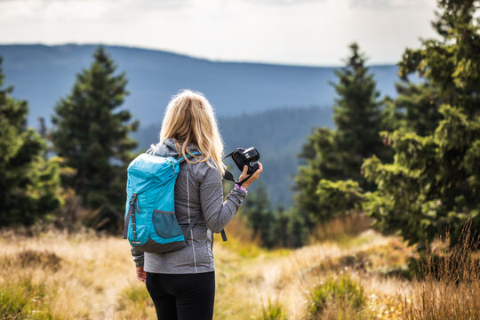Woman photographer with backpack and camera hiking in  mountains. Adventure in nature
