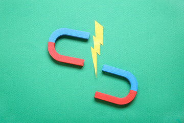Paper lightning with horseshoe shaped magnet on green background