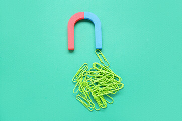 Magnet with heap of paper clips on green background