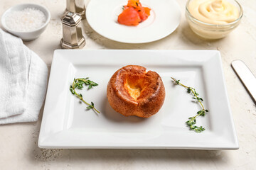 Plate with tasty Yorkshire pudding on light background