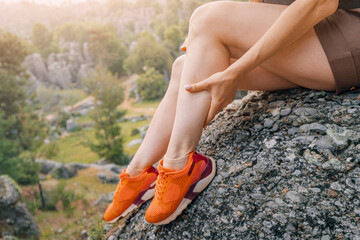 A girl massages the calf of her leg after an injury or stretching of a muscle during a hike © EdNurg