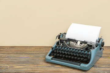 Vintage typewriter on brown wooden table near beige wall