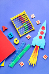 Paper rocket with abacus, wooden letters and different stationery on dark blue background