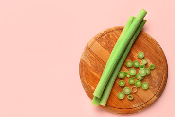Board with slices of fresh leek on pink background
