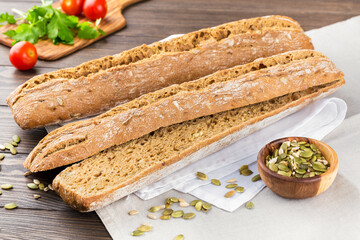 Grain baguette on white napkin on wooden background