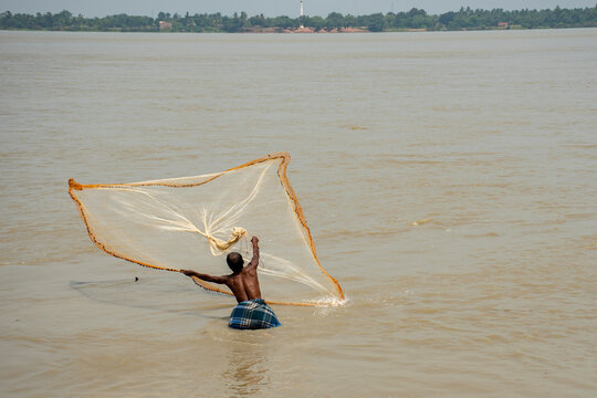 5th June, 2023, Burul, West Bengal, India: A fisherman throwing his fishing net at water for catching fish.