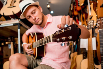 Young musician tuning a classical guitar in a guitar shop