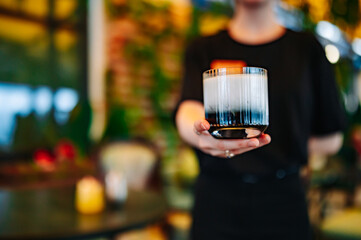 waiter hand hold cocktail glass in bar