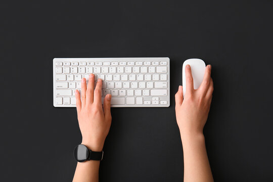 Female hands with modern computer keyboard and mouse on dark background