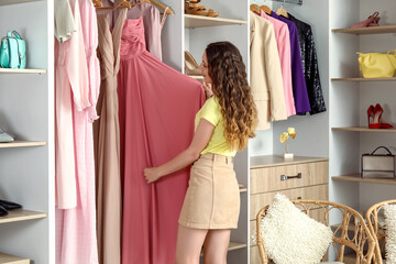 Young woman choosing dress for prom in shop