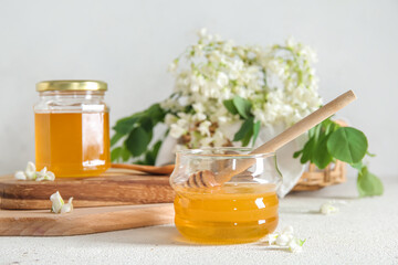 Composition with sweet honey and acacia flowers on light background, closeup