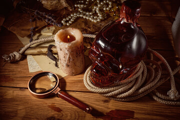 Vintage pirate still life with candle, compass, dark rum in a skull bottle and old papers